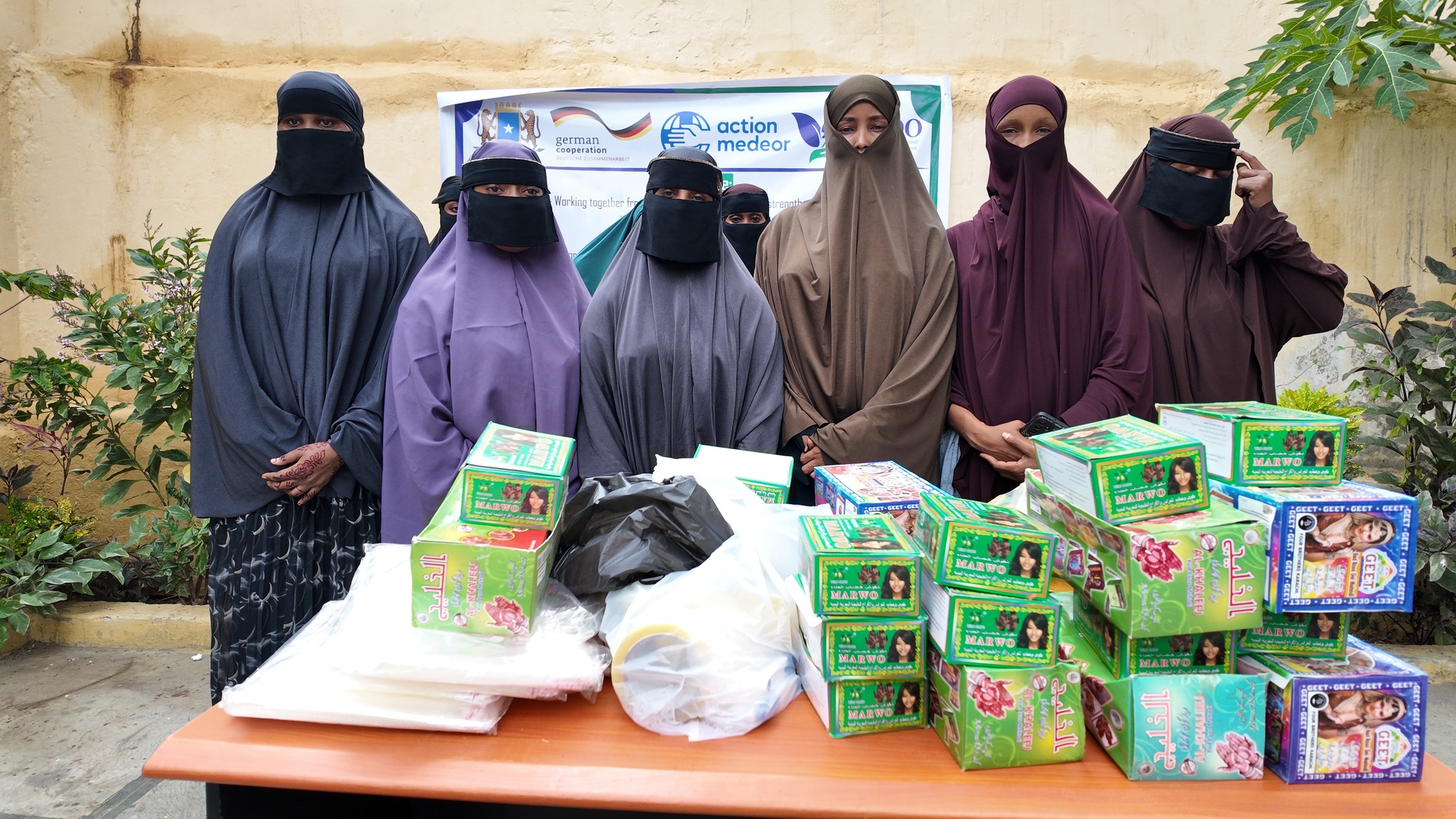 Women standing with henna and livelihood supplies after a HURDO skills activity